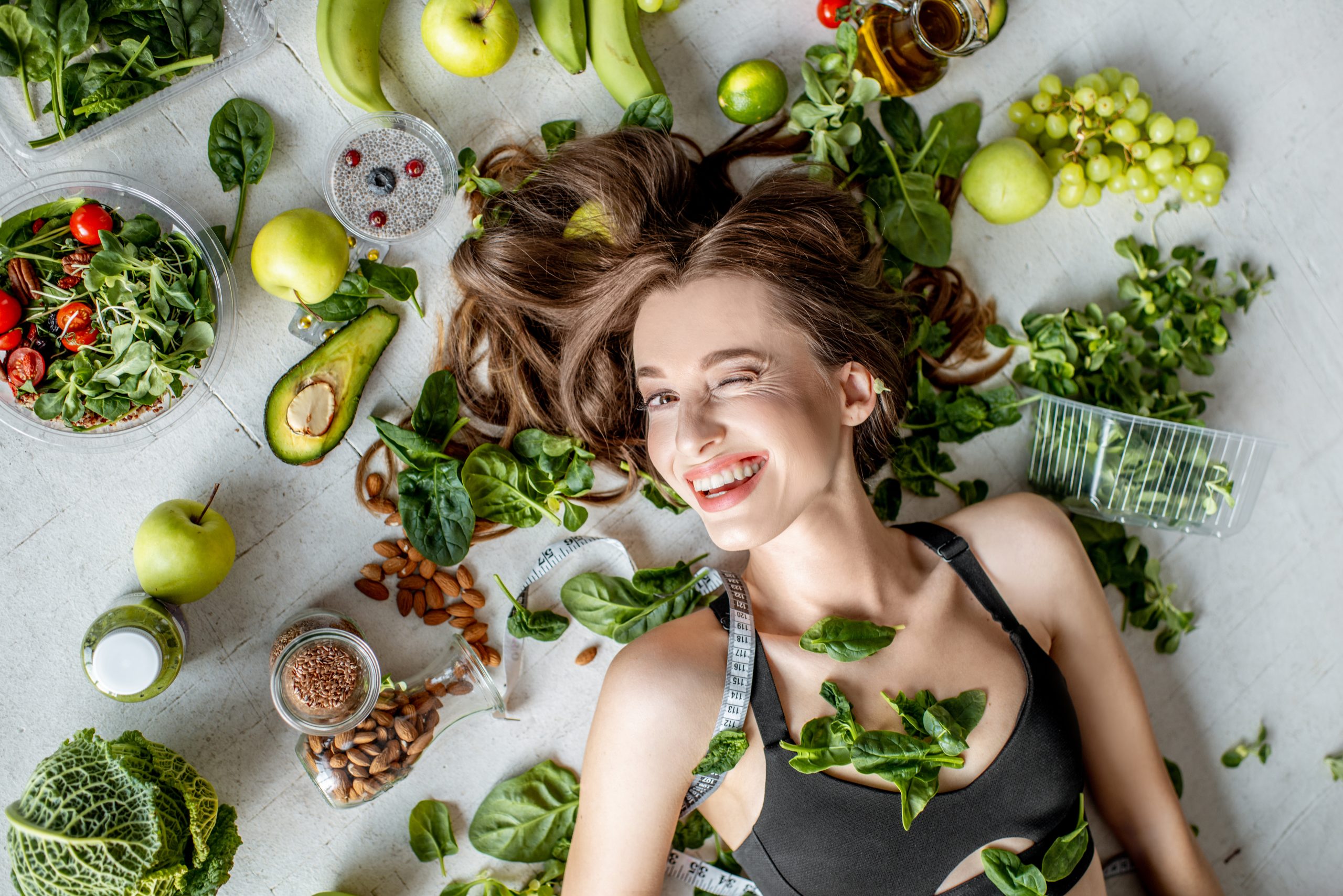 natural ingredients surround by a lady, banana, green leaf, avocado, berries, nuts