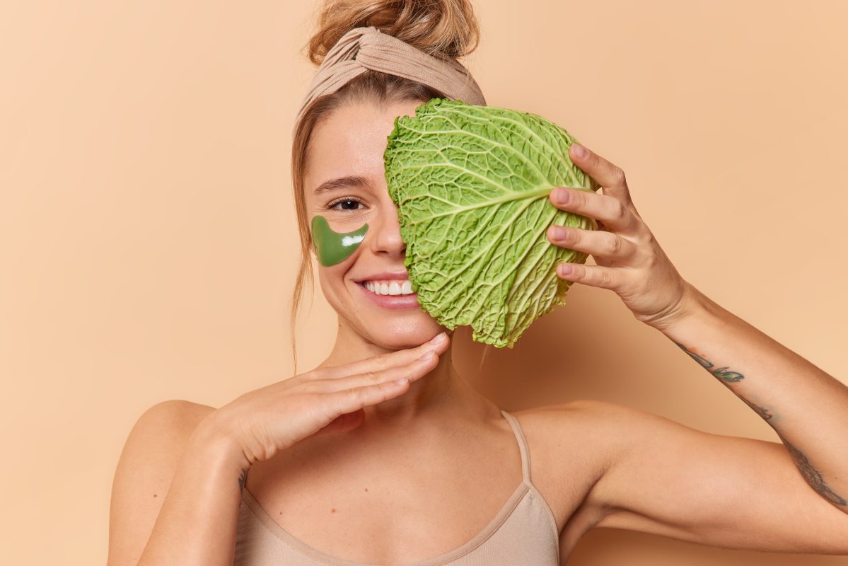 Woman with radiant skin holding leafy greens, illustrating the gut-skin health connection.